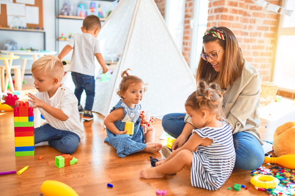 Erzieherin sitzend mit vier tobenden Kindern